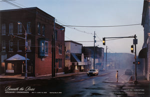 Exhibition poster from Gregory Crewdson's 2005 show "Beneath the Roses," showing a large photo of a woman standing at a streetlight. 