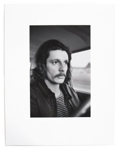 Image from Larry Clark's "Kiss the Past Hello" set. Black and white photograph of a man at the wheel of a car.